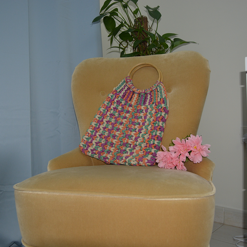 Multicolor handwoven macrame bag with wooden handle.