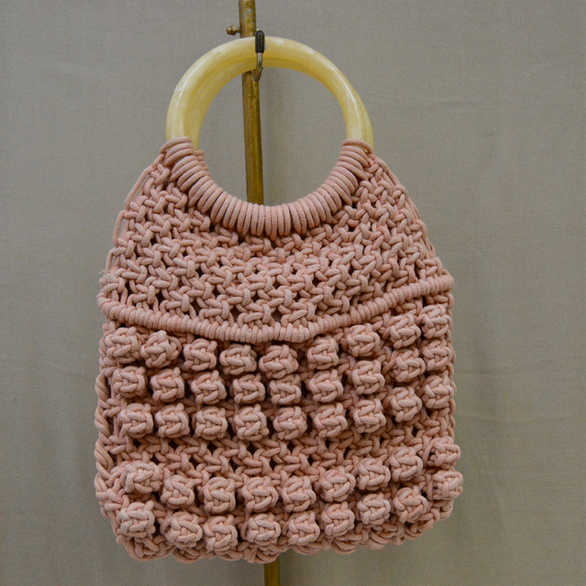 Peach color handwoven macrame bag with plastic handle.