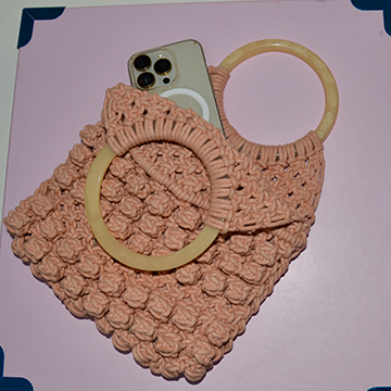 Peach color handwoven macrame bag with plastic handle.